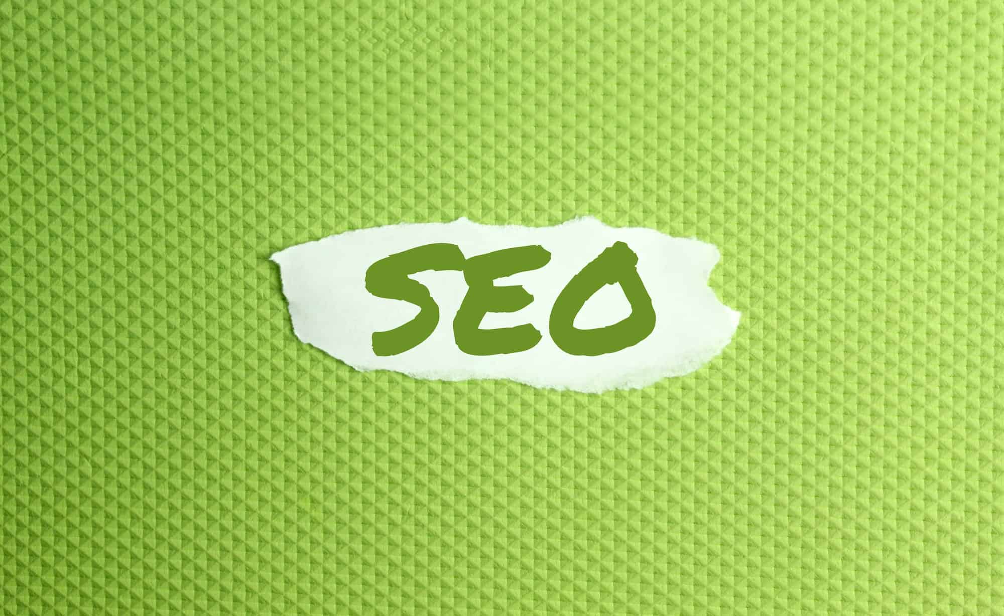 a torn paper written with inscription SEO on a green background