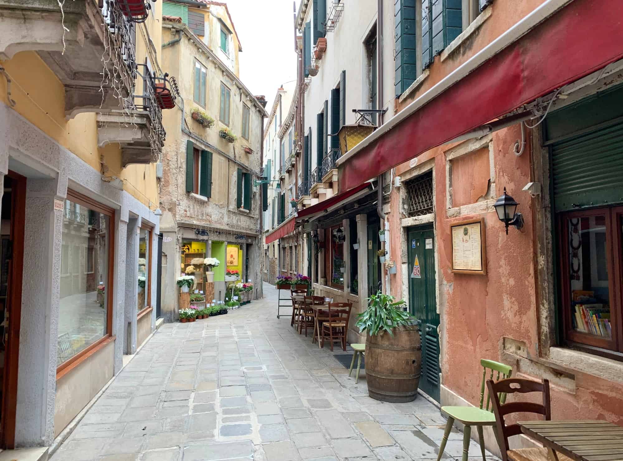 Picturesque alley way and pedestrian street of venice with a flower stores and restaurants